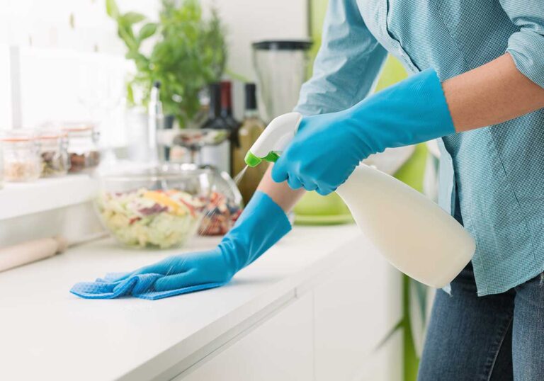 Person cleaning a large household window with a squeegee and microfiber cloth on a cloudy day.